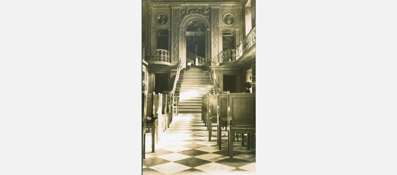 Benches set out in rows for assembly and chapel services in the Painted Hall. Note the hassocks for the choir piled at the end of each step on the staircase. 